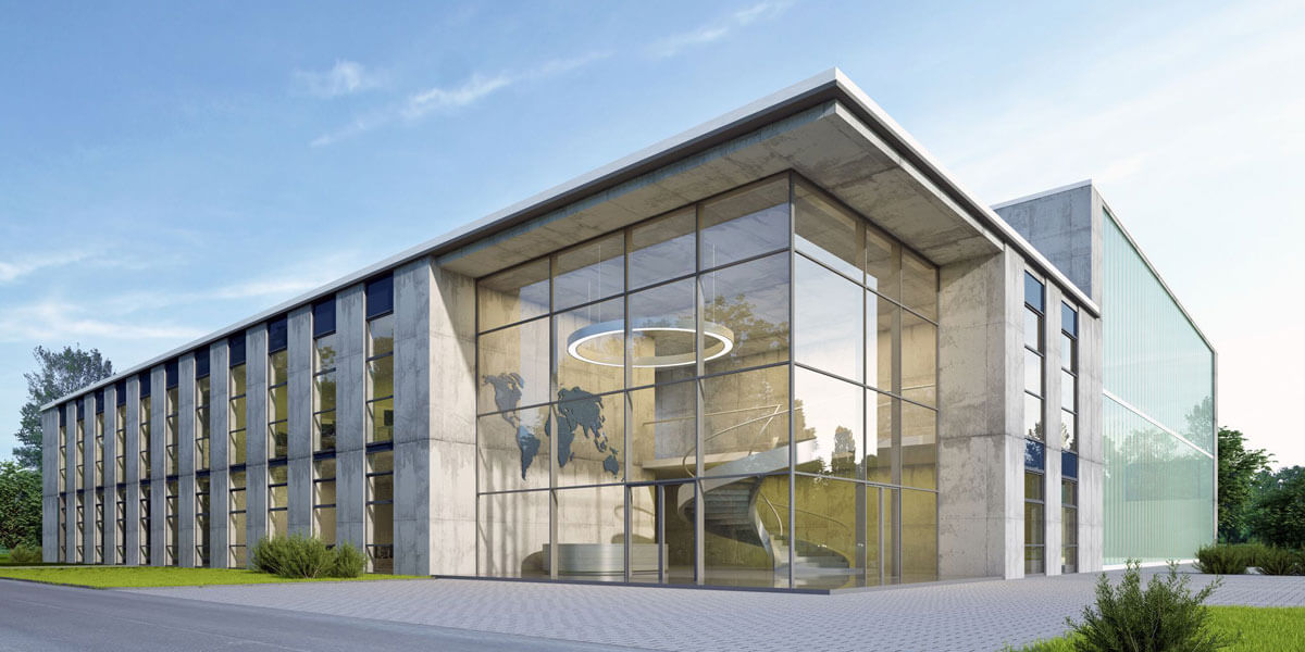 A modern building with large glass windows and sleek architectural lines stands surrounded by greenery under a clear sky.