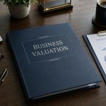 A business valuation binder on a desk with a pen, calculator, plant, cup of coffee, and a financial analysis report with charts.